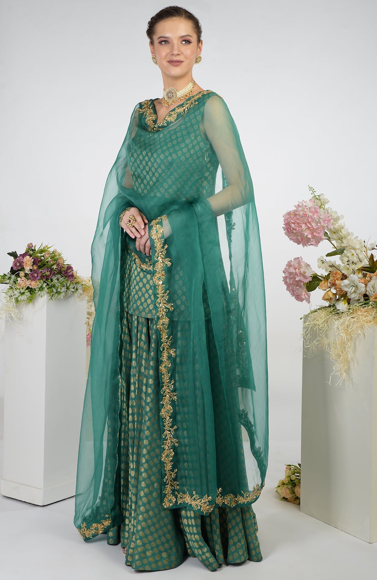 A woman models a bottle green Banarasi zardozi kalidaar skirt set with a sheer dupatta.