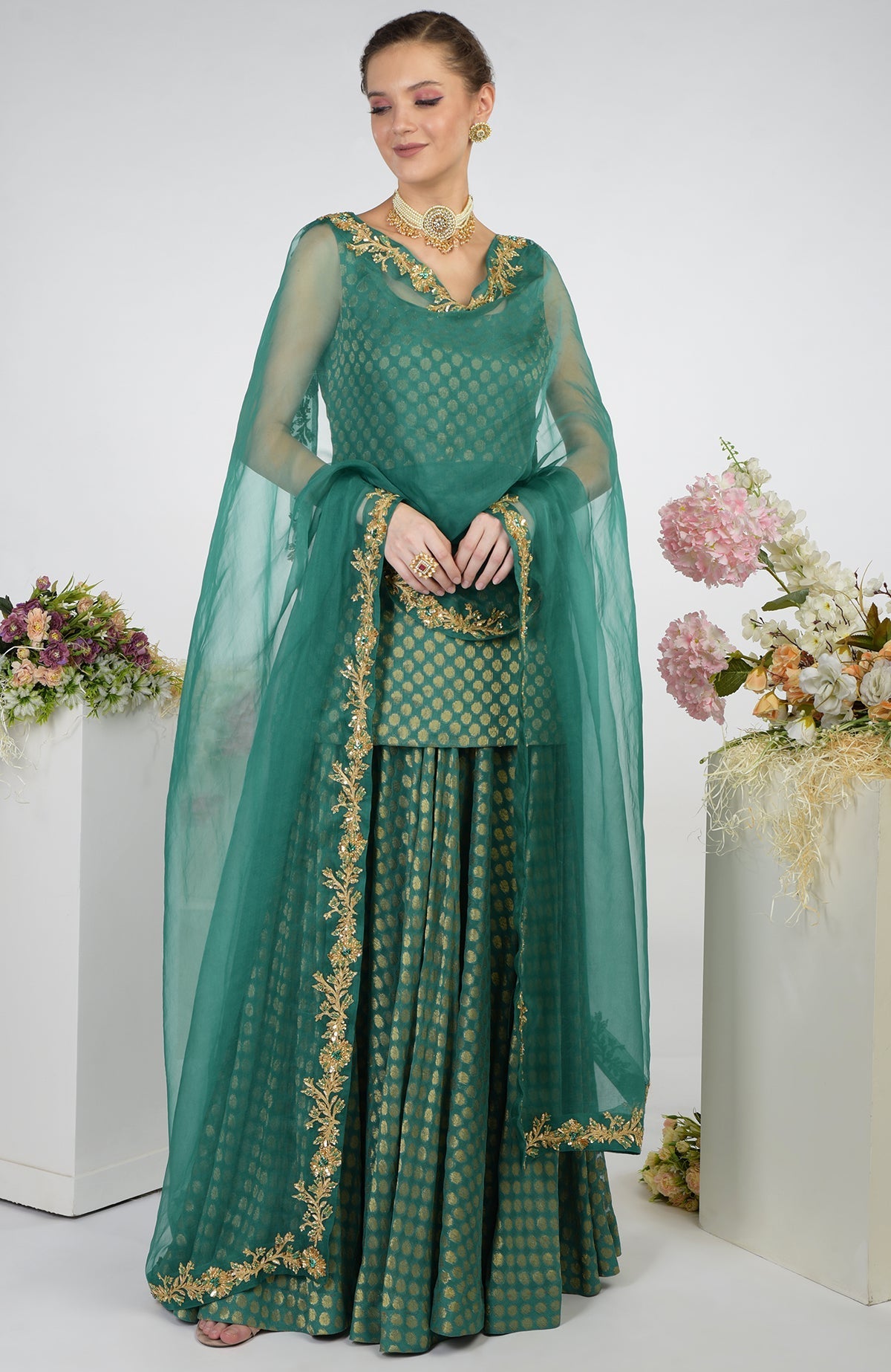 A woman models a bottle green Banarasi zardozi kalidaar skirt set.