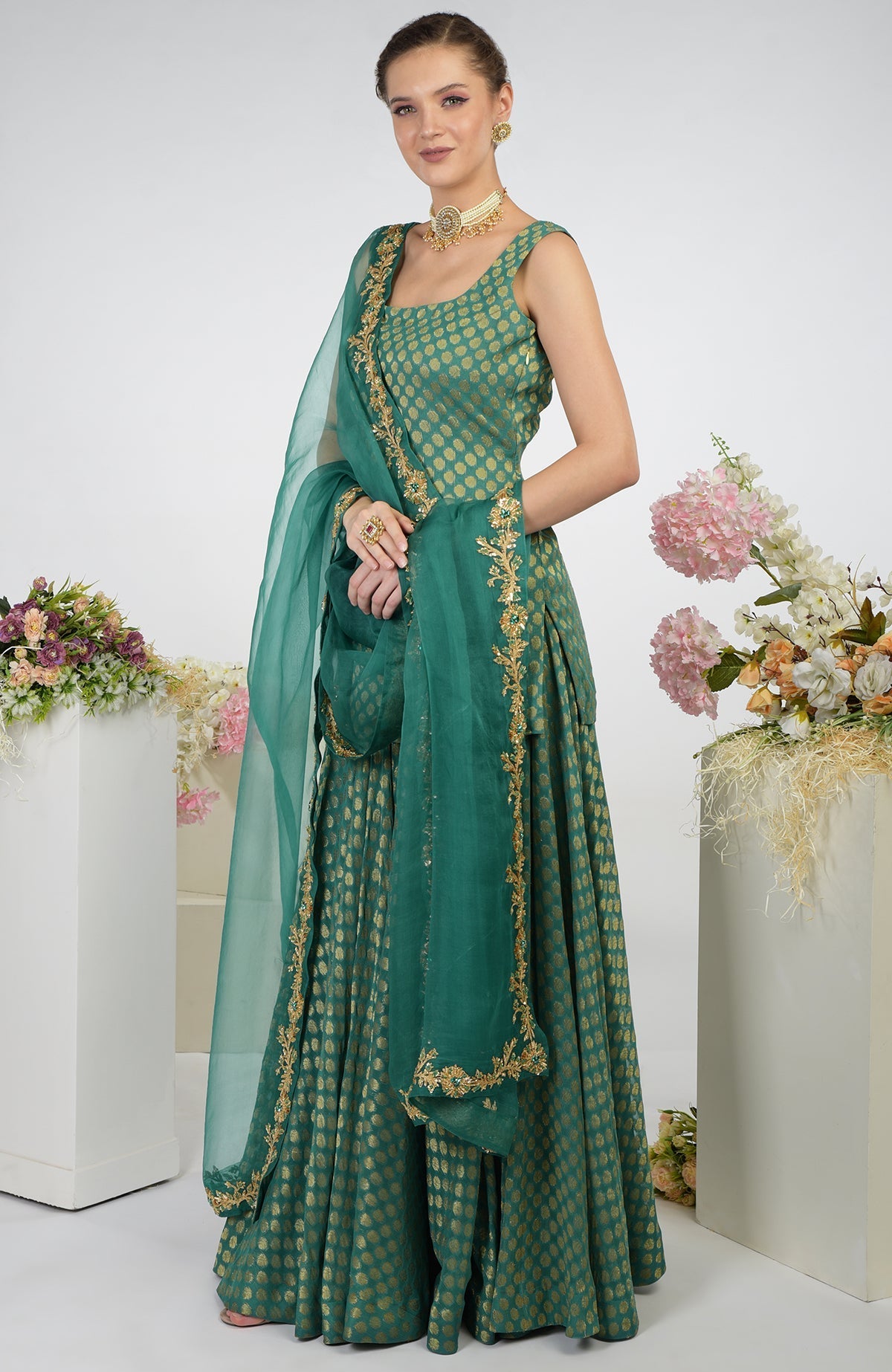 A woman models a bottle green Banarasi zardozi kalidaar skirt set with gold embroidery.