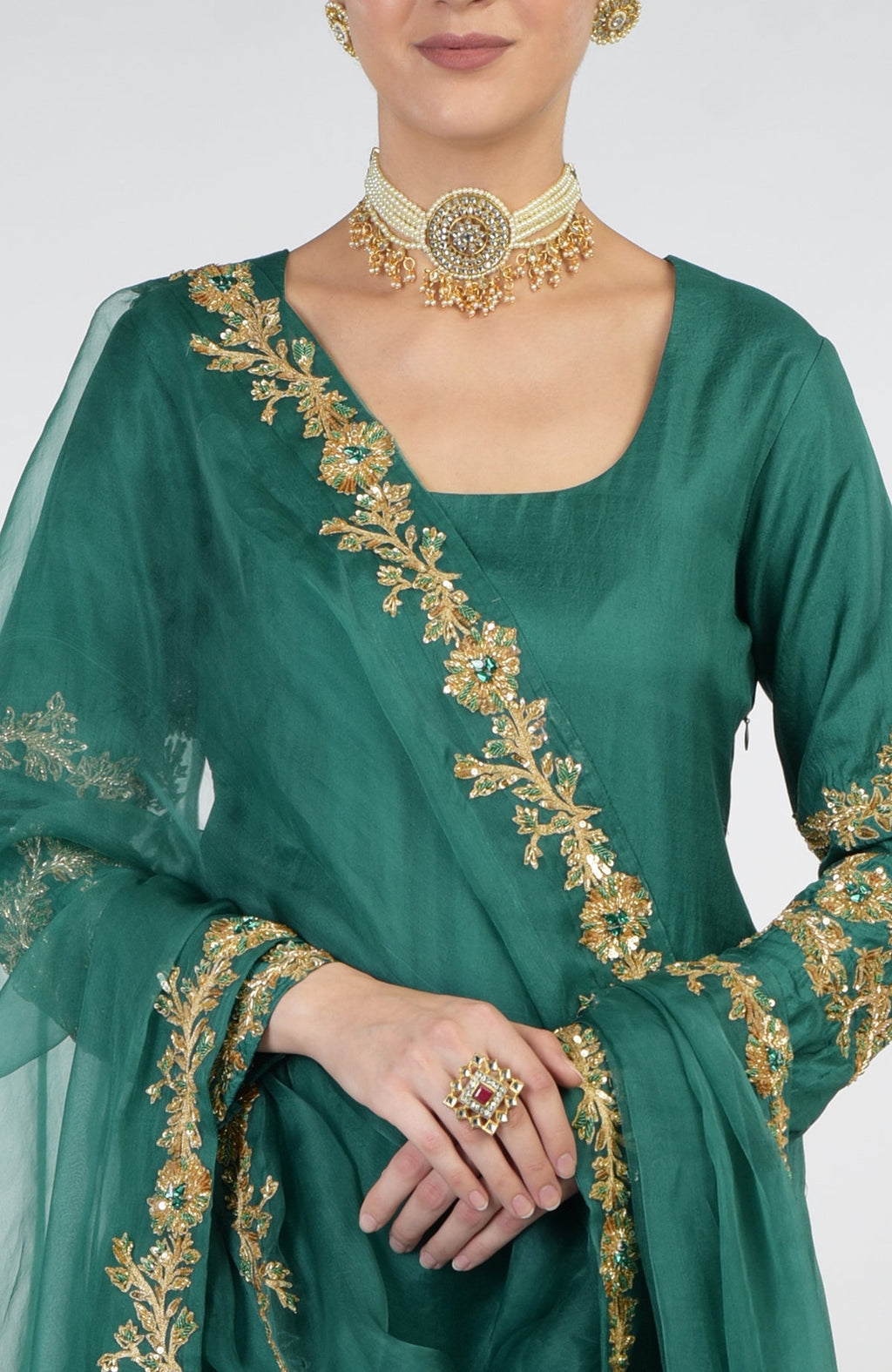 A woman models a bottle green Banarasi zardozi kalidaar skirt set with a pearl choker.