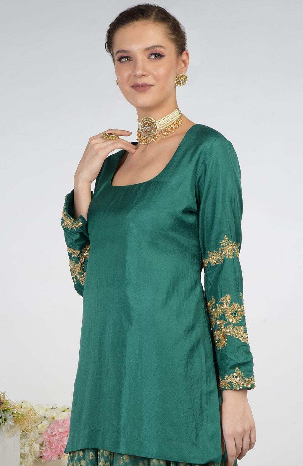 A woman models a bottle green Banarasi Zardozi Kalidaar skirt set with embroidered sleeves.
