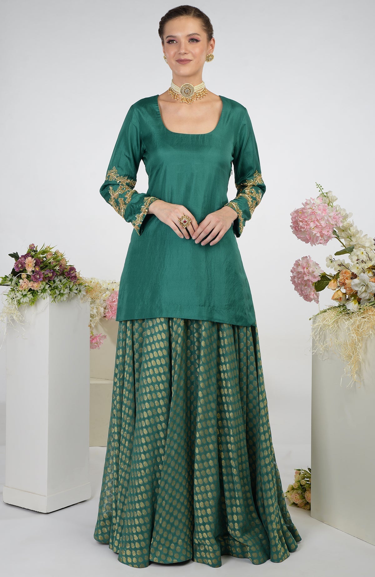 A woman models a bottle green Banarasi Zardozi Kalidaar Skirt Set with gold embroidery.