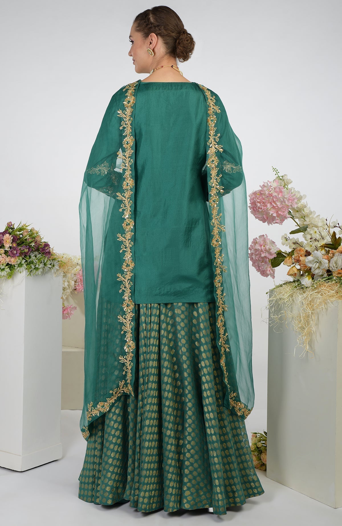 A woman models a bottle green Banarasi zardozi kalidaar skirt set.
