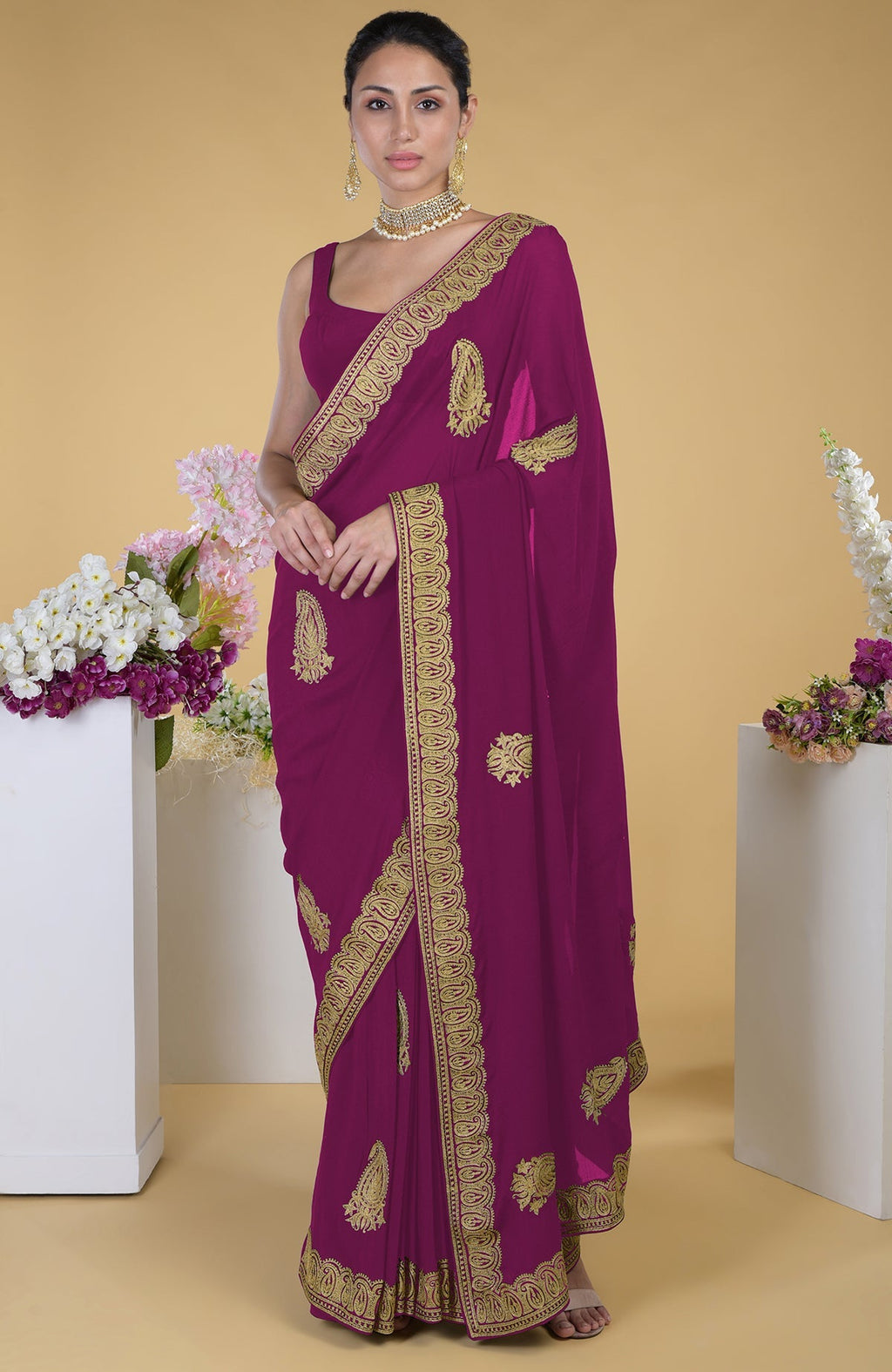 A woman models a peacock pink-gold Kashmiri Tilla Aari embroidered saree.