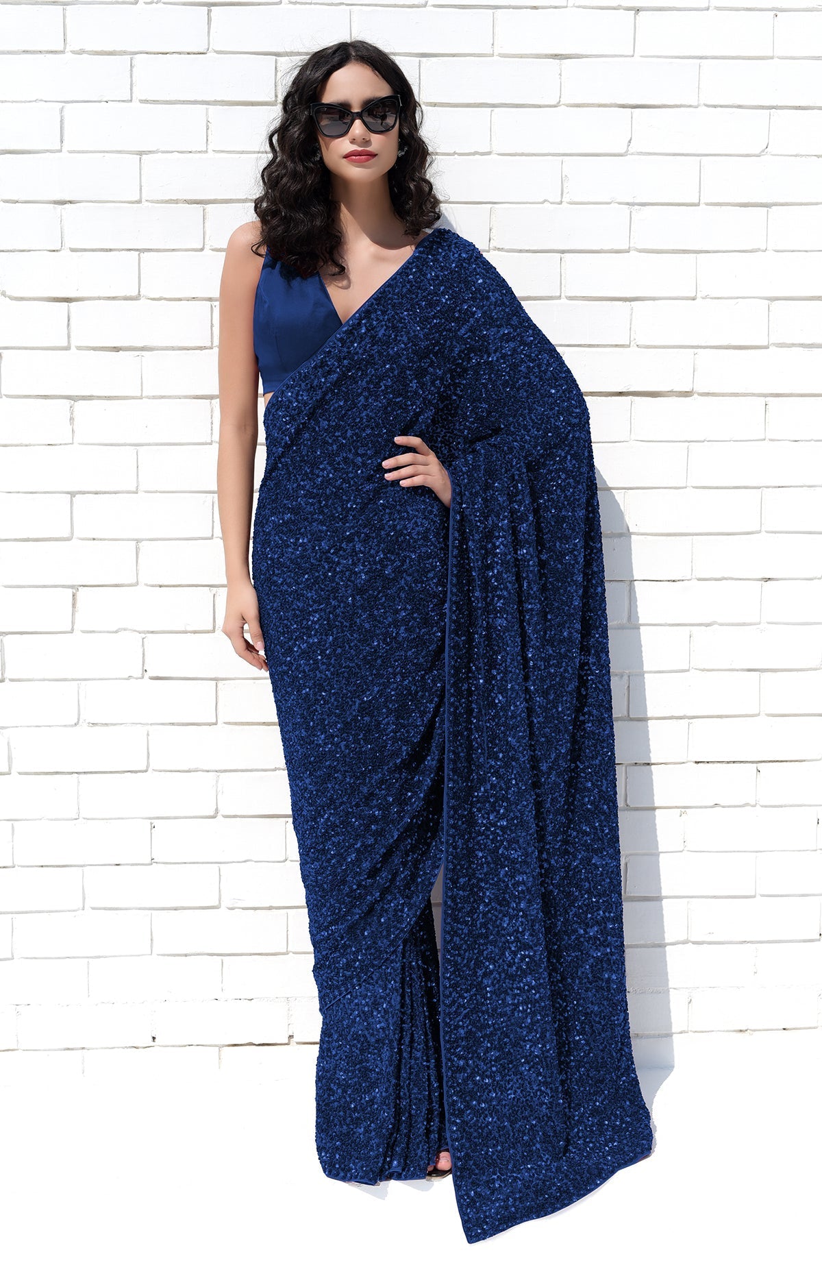 A woman models a sapphire blue sequin saree with a matching satin blouse.