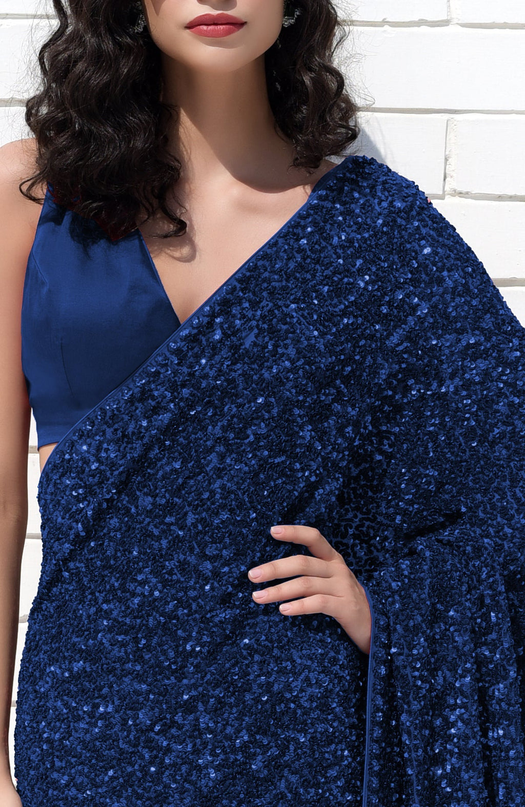 A woman models a sapphire blue sequin saree with a matching satin blouse.