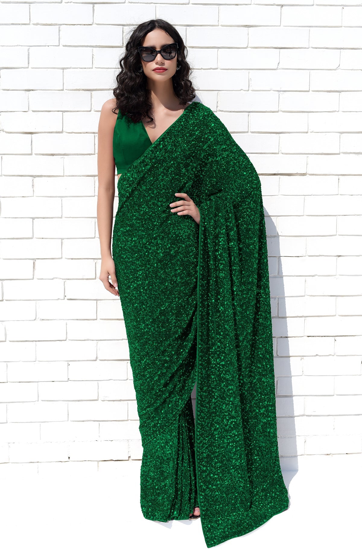 Woman in an emerald green sequin saree and matching blouse.