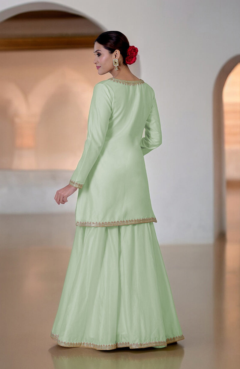 A woman models a sage green sharara set with gold embroidery.