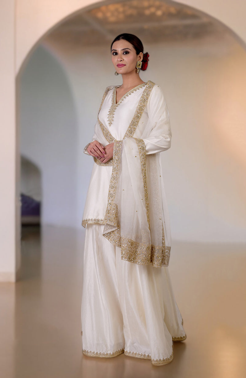 An elegant ivory sharara set with gold marori and zardozi hand embroidery.