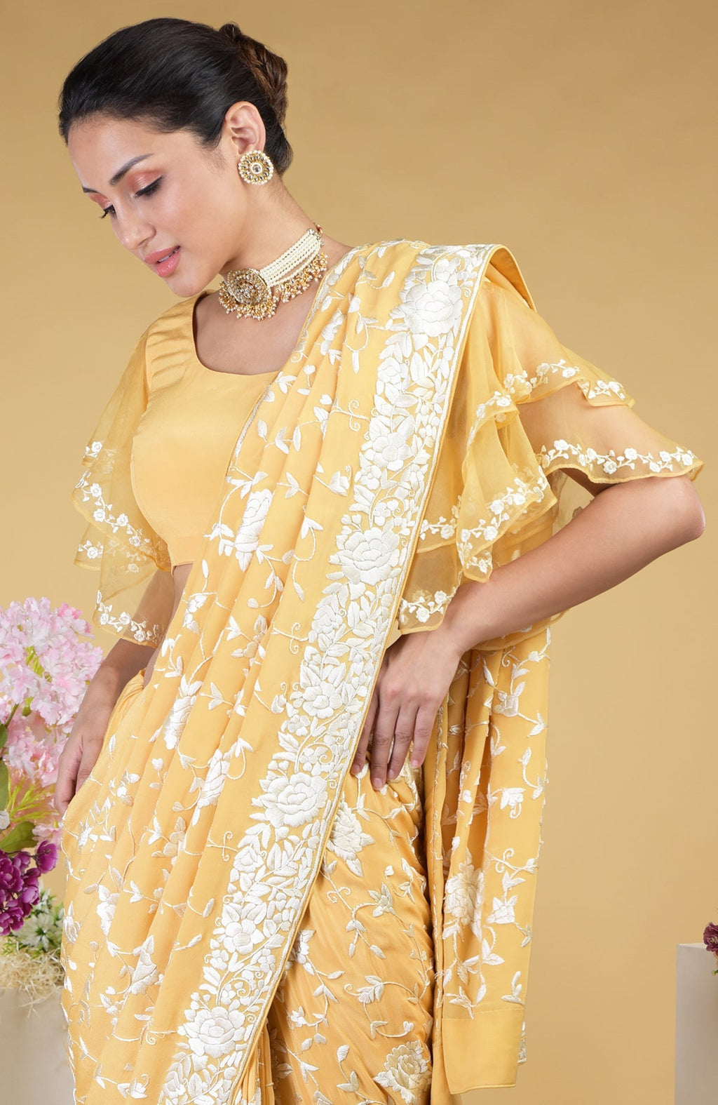 A woman models a mango yellow Parsi Gara hand-embroidered saree with a frill-sleeved blouse.