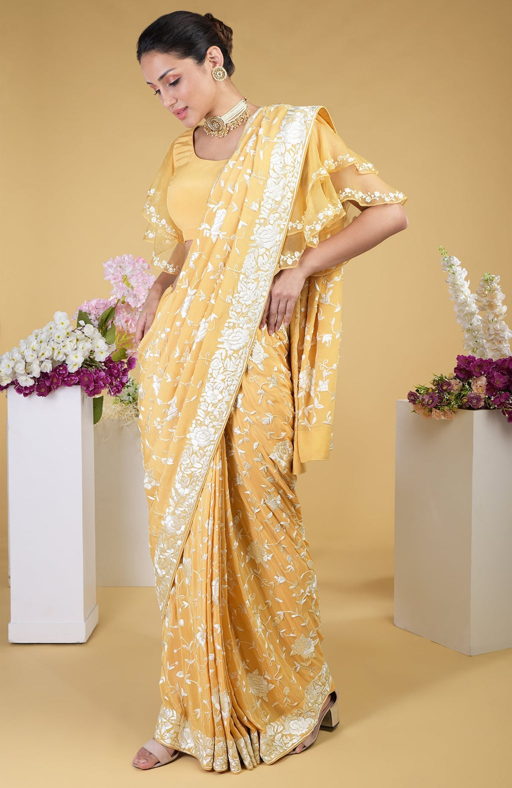 A woman models a mango yellow Parsi Gara hand-embroidered saree with a frill blouse.
