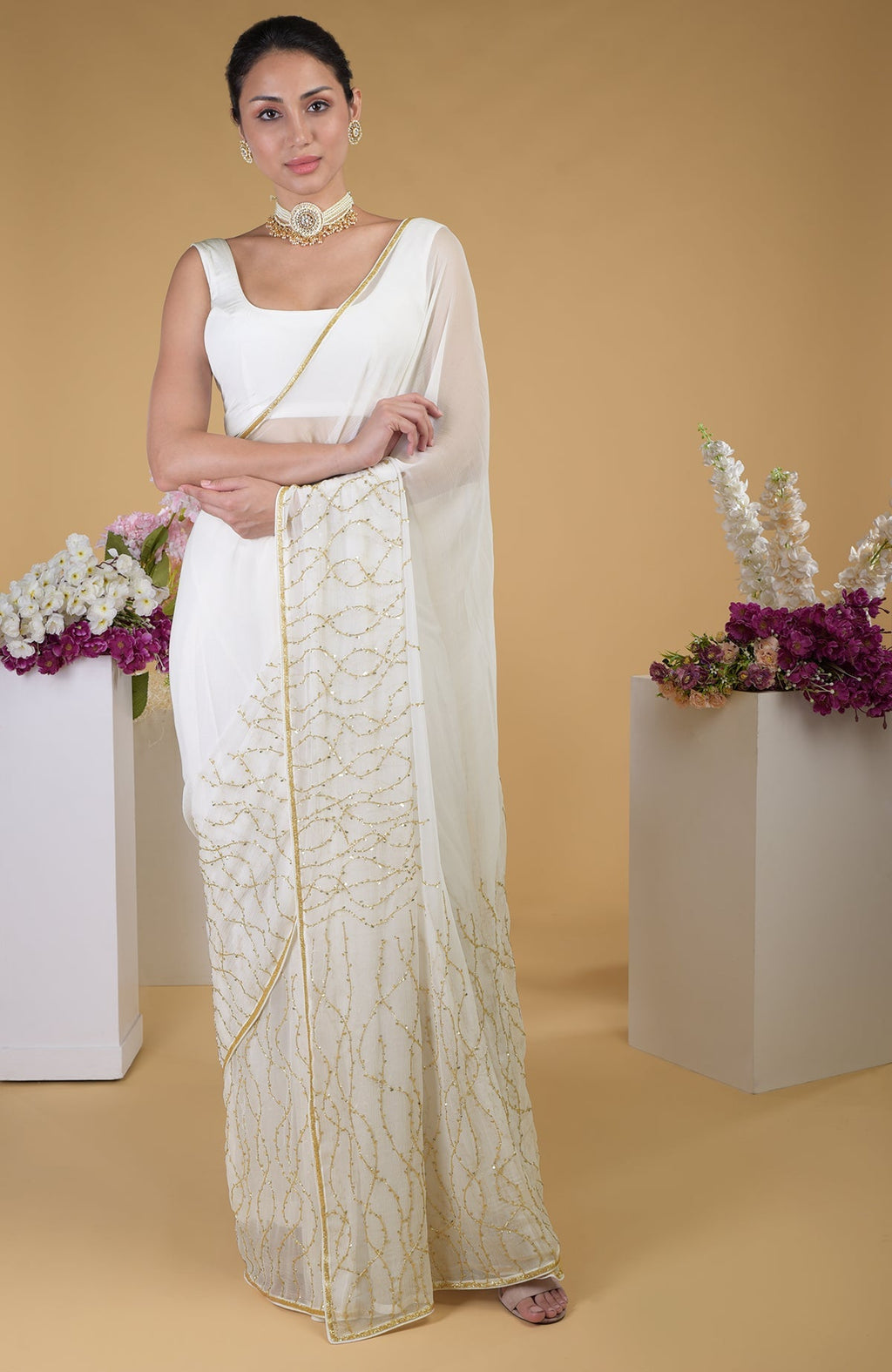 An ivory gold beads and sequin zardozi hand-embroidered saree with a scoop neck blouse.