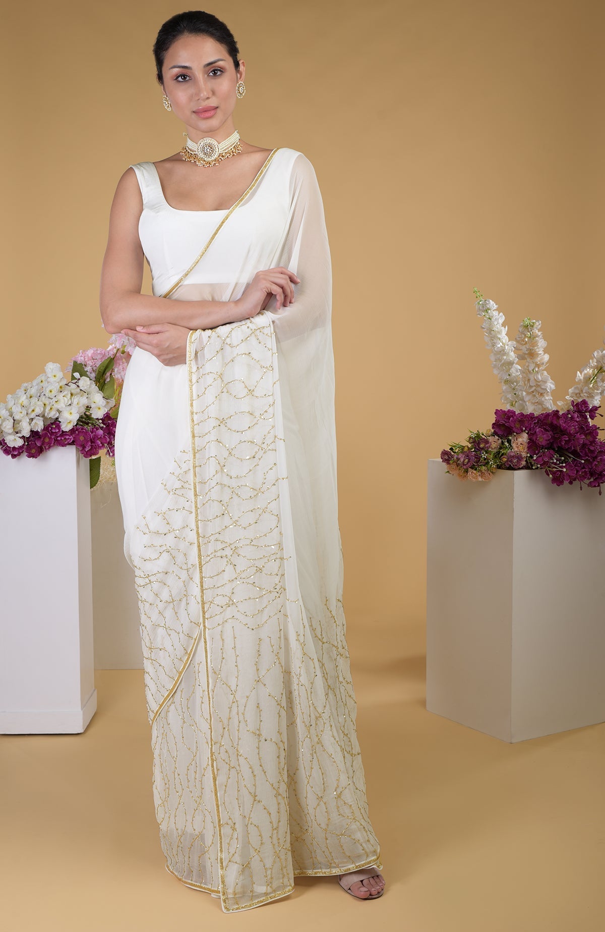 An ivory gold beads and sequin zardozi hand-embroidered saree with a scoop neck blouse.