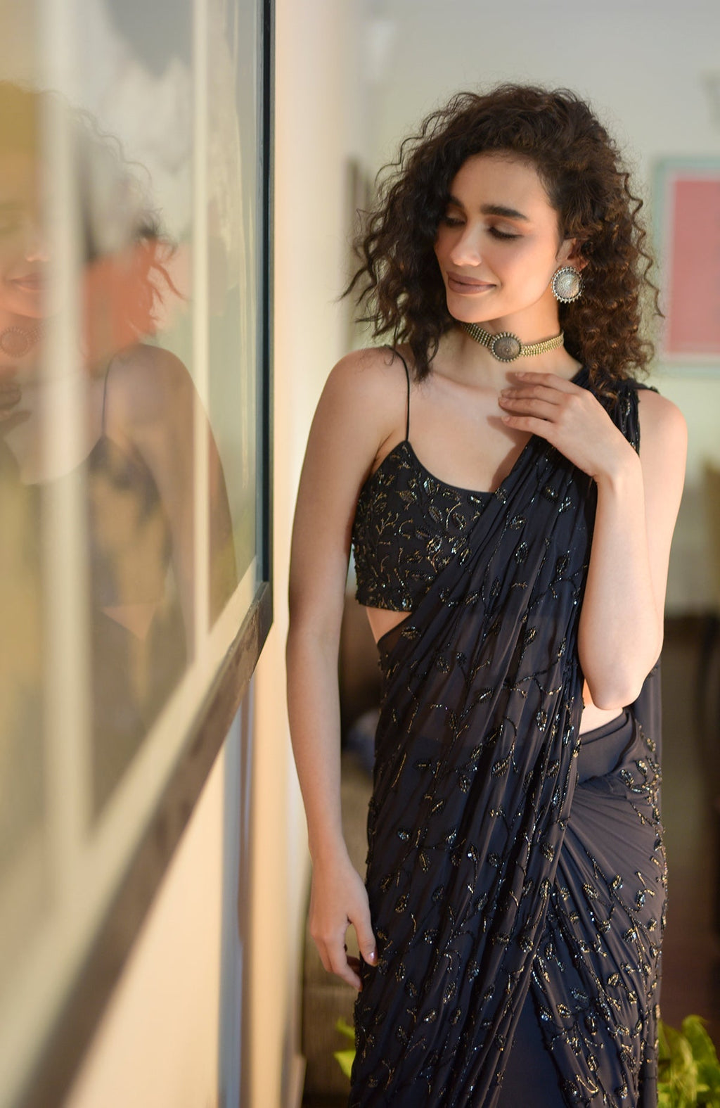 A woman models a black hand-beaded embroidered draped gown saree with a matching blouse.