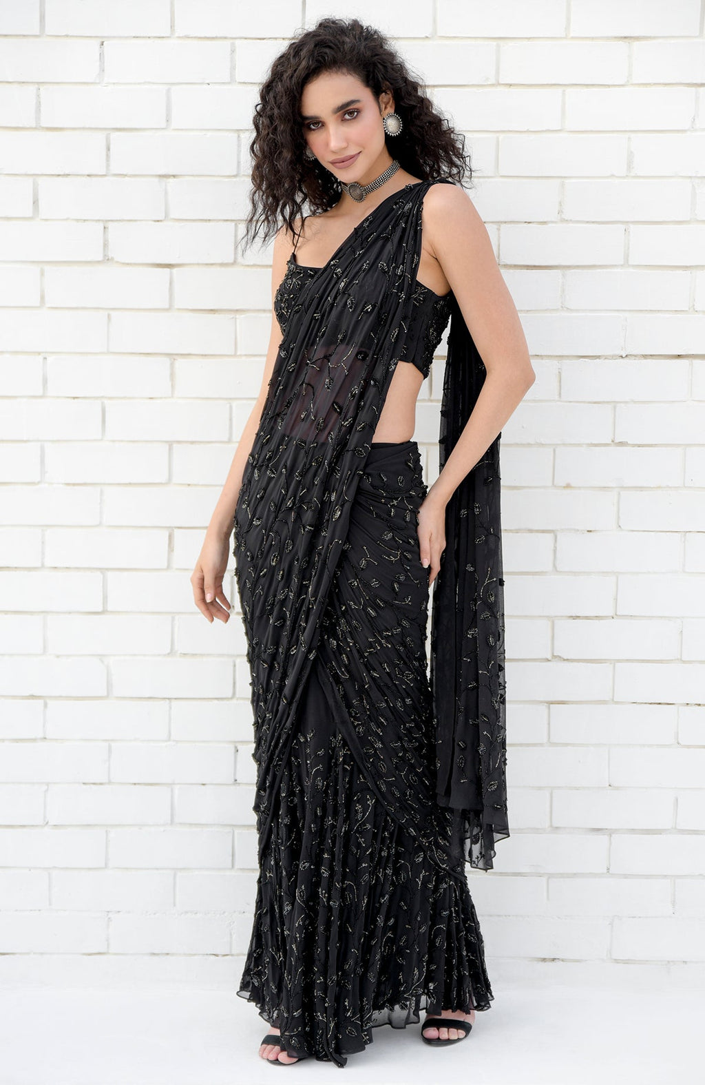 A woman models a black hand-beaded embroidered draped gown saree with a matching blouse.