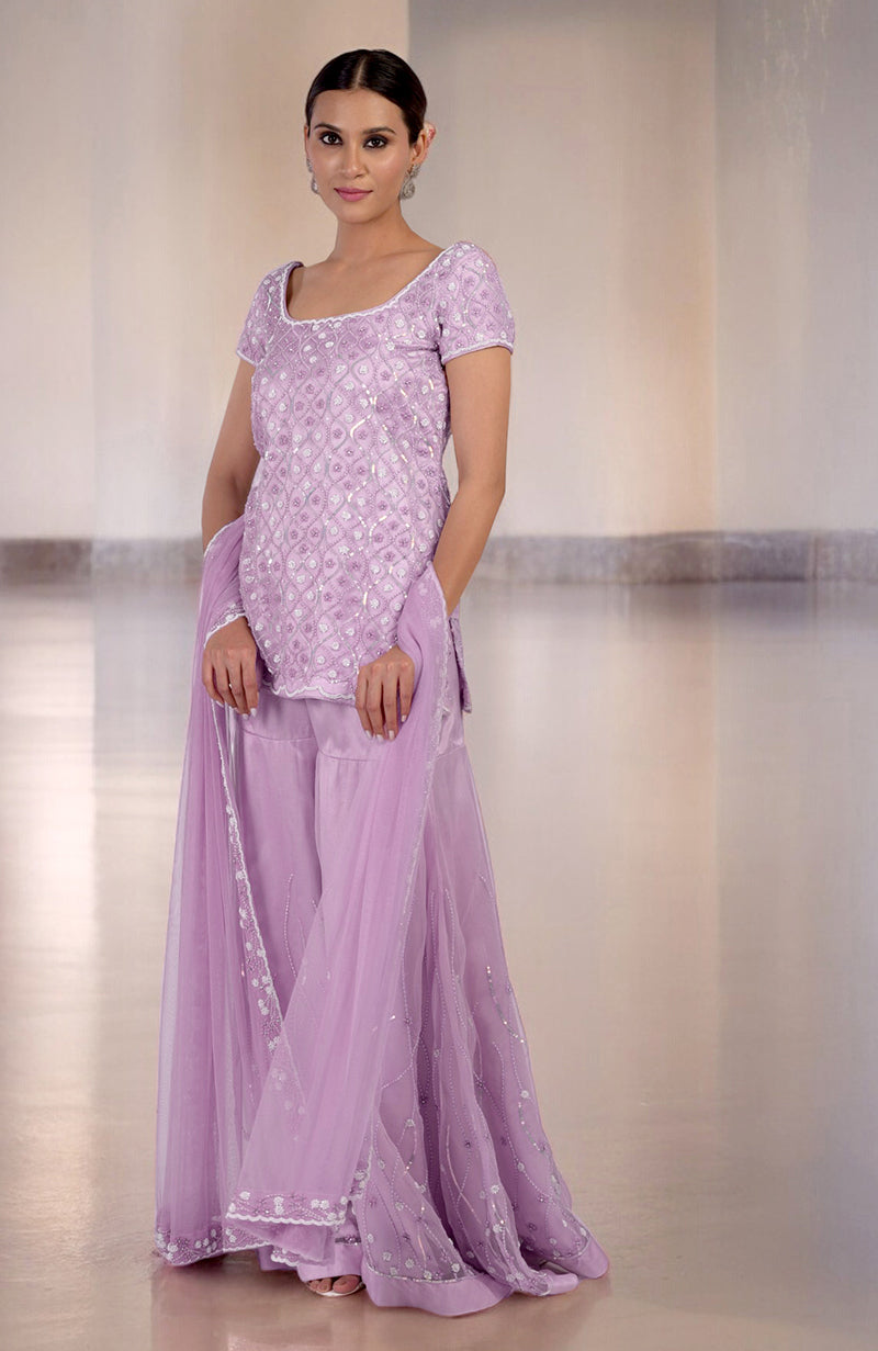 A woman models a lilac silk organza hand-beaded sharara set with a matching dupatta.