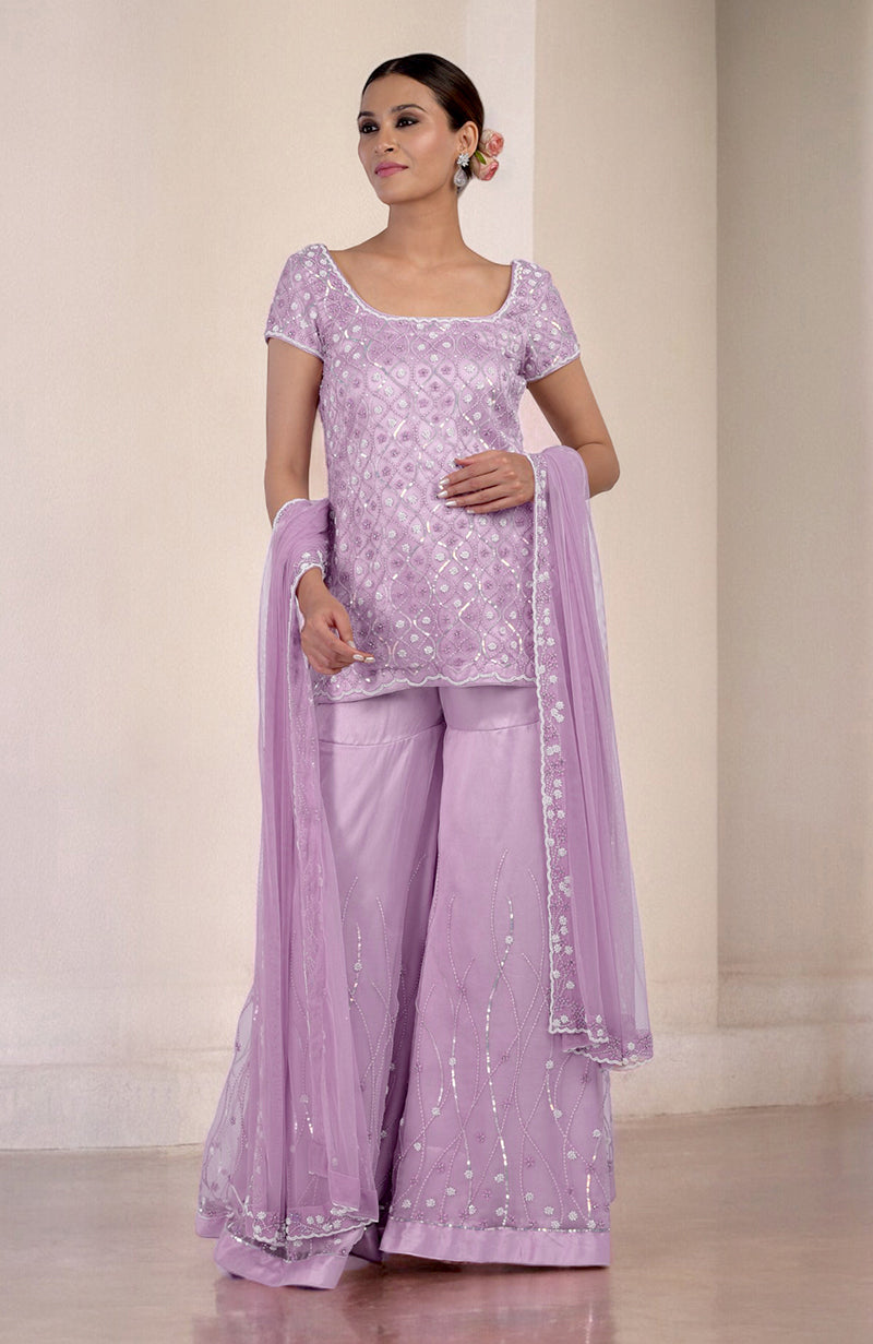 A woman models a lilac silk organza hand-beaded sharara set with a matching dupatta.