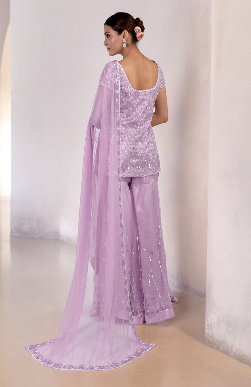 A woman models a lilac silk organza hand-beaded sharara set with a long dupatta.