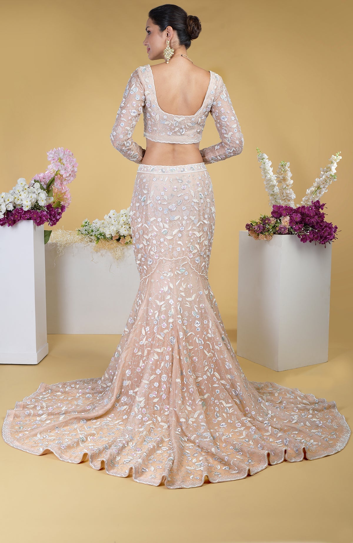 A woman from behind models a peach embroidered mermaid-style skirt and matching blouse.