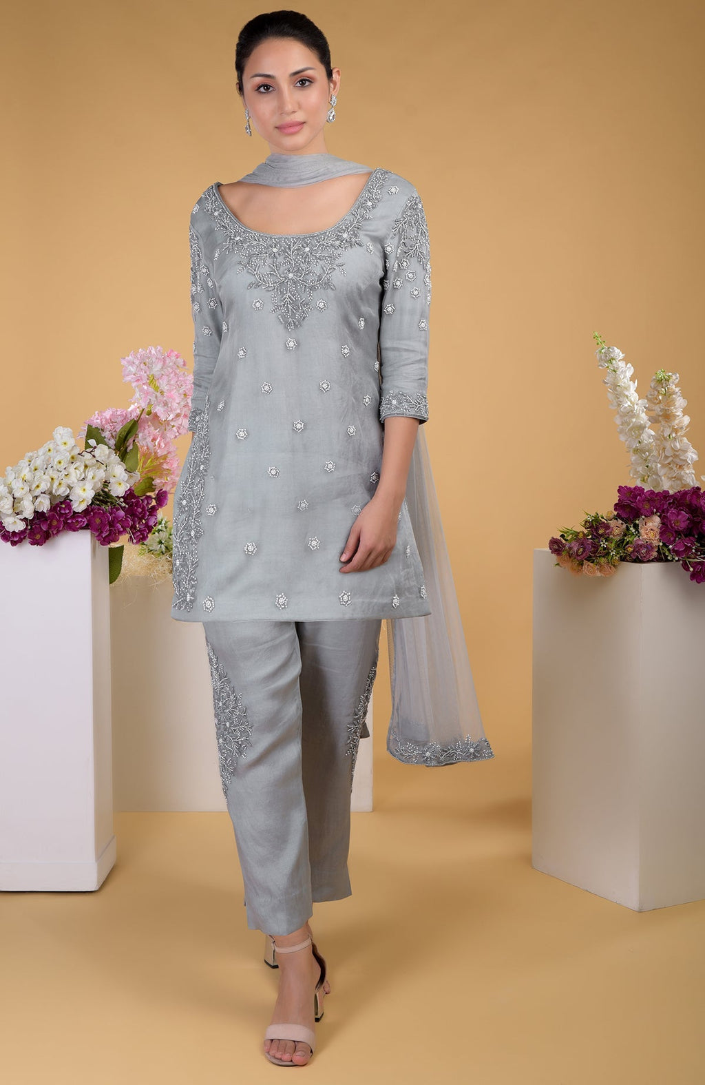 A woman models a grey silk organza hand-embroidered kurta set with a matching dupatta.