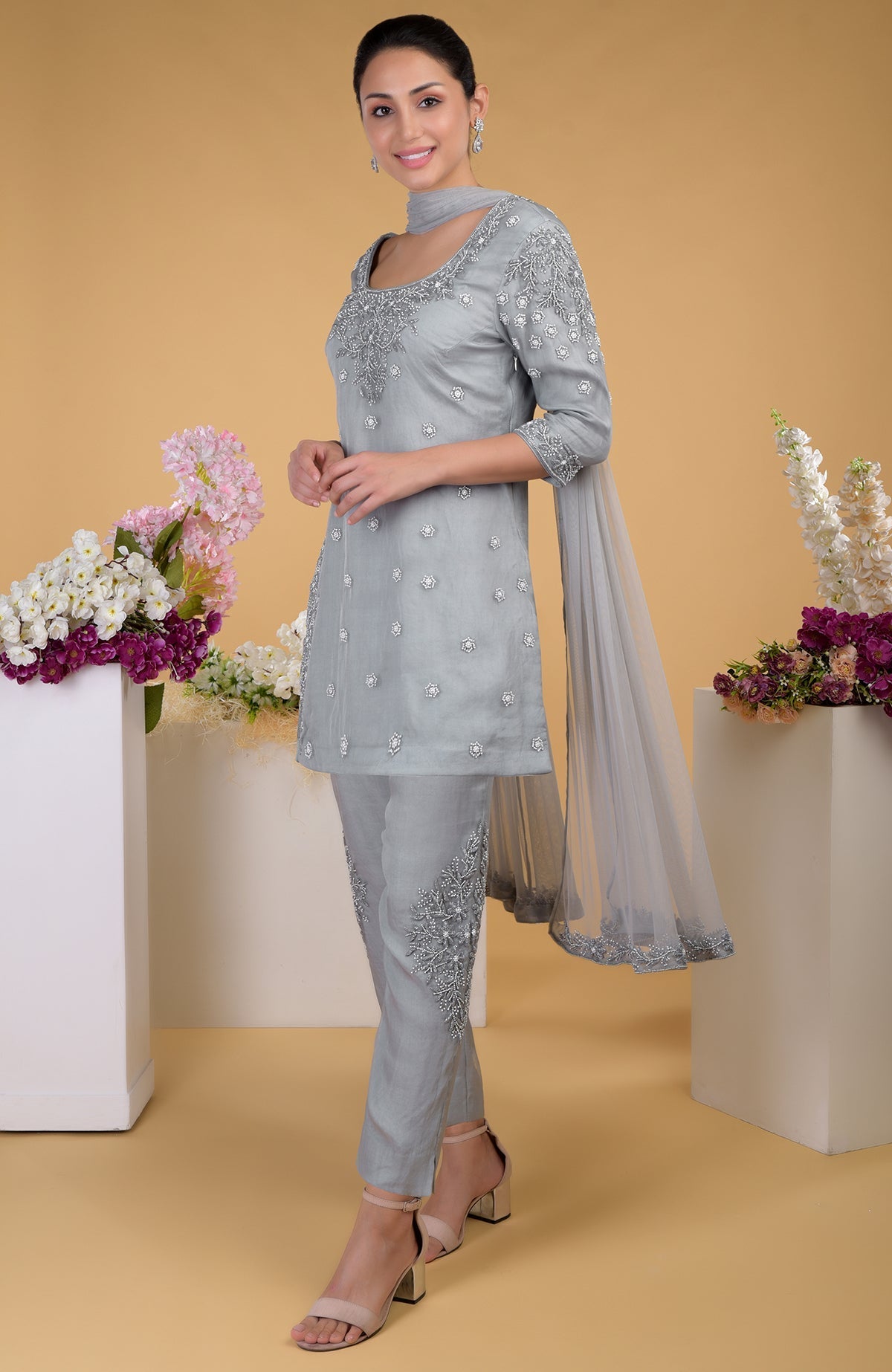 A woman models a grey silk organza hand-embroidered kurta set with a matching dupatta.