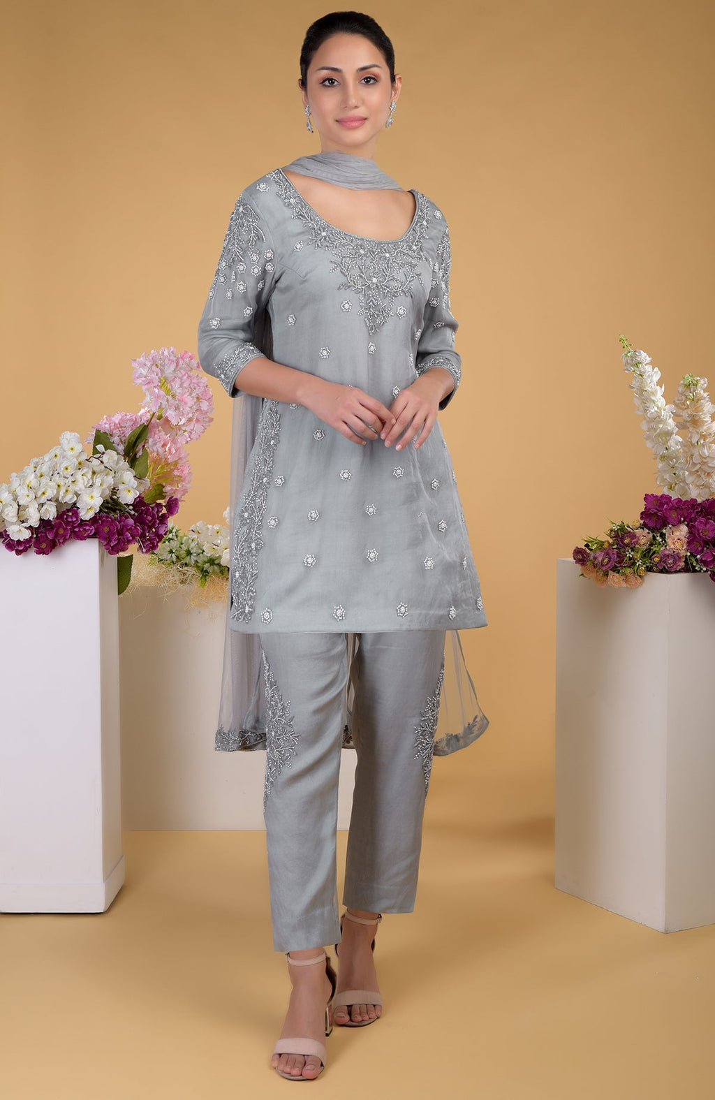 A woman models a grey silk organza hand-embroidered kurta set with a matching dupatta.