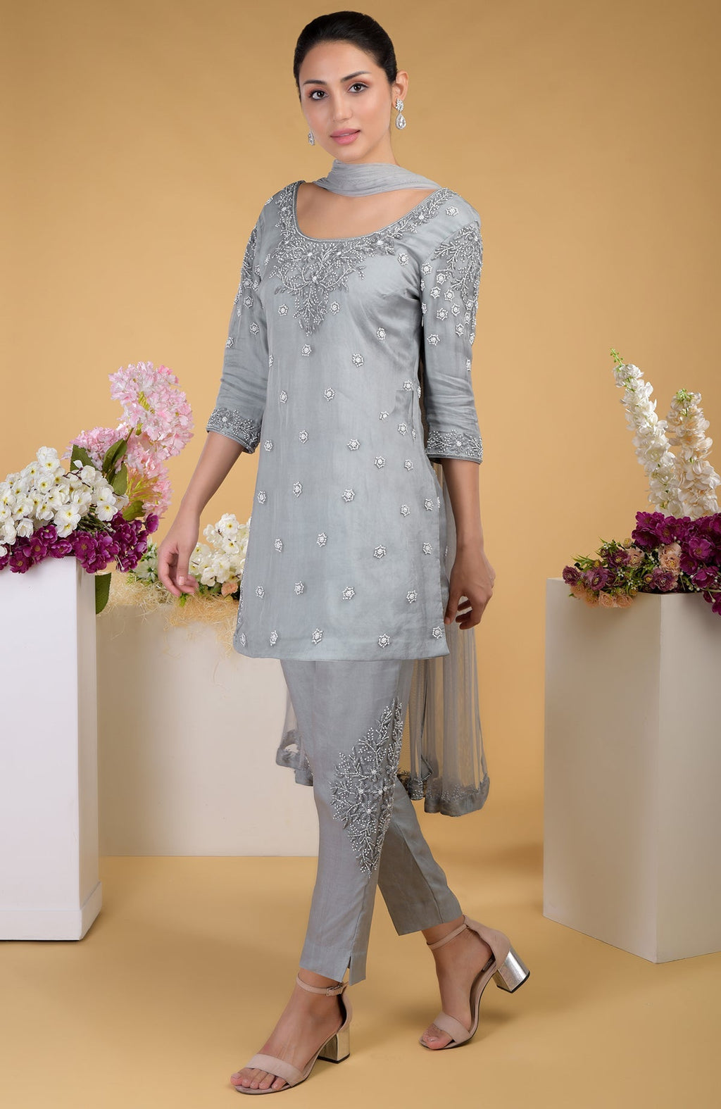A woman models a grey silk organza hand-embroidered kurta set with matching dupatta.