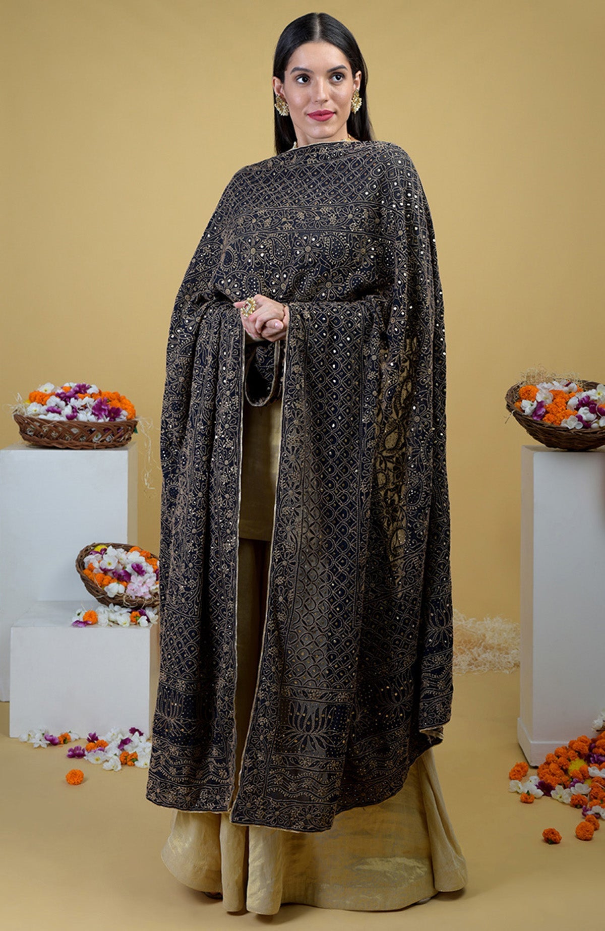 A woman in a black chikankari and kamdani dupatta with a gold tissue sharara suit.