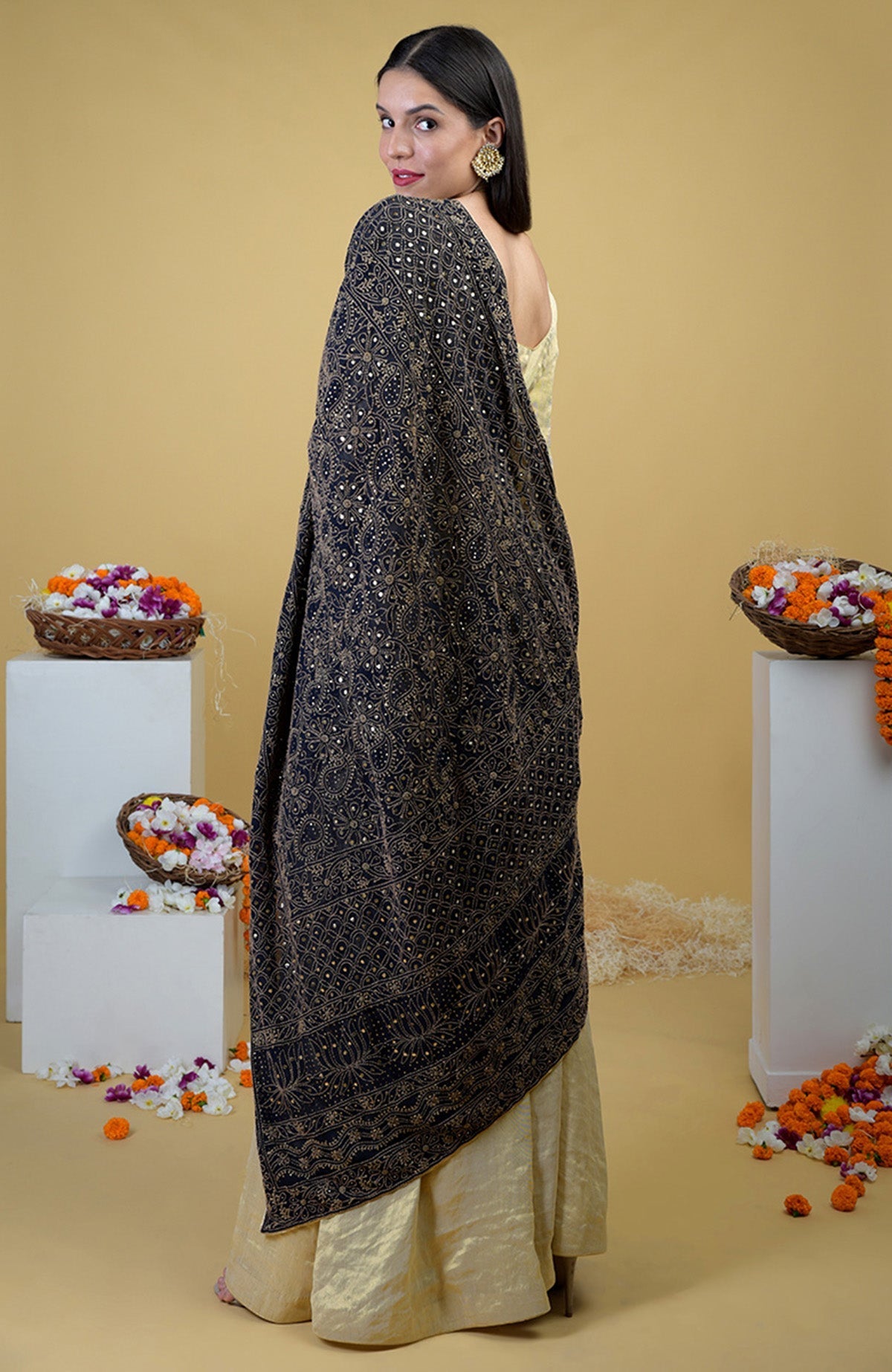 Woman in a black chikankari and kamdani dupatta with a gold tissue sharara suit.