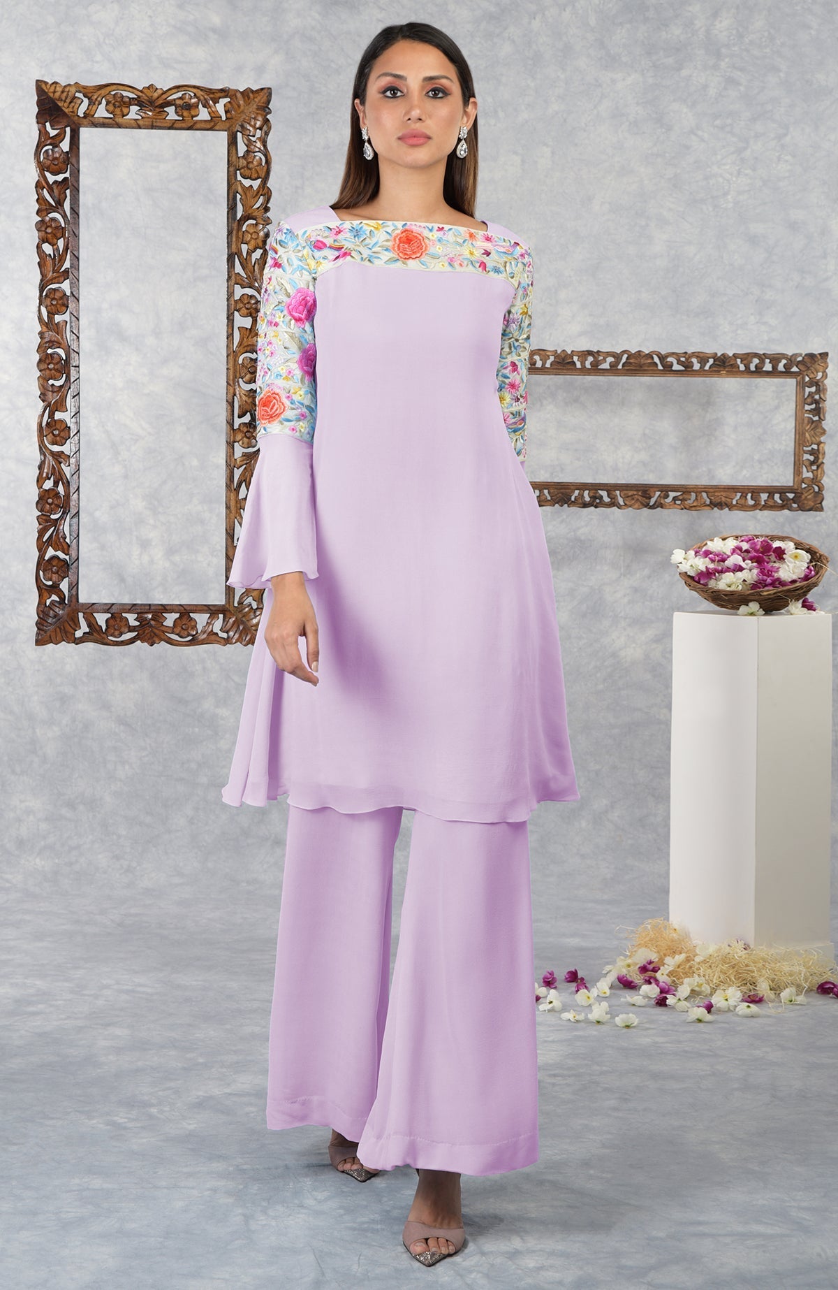 A woman models a lilac Parsi Gara embroidered kurta set with bell sleeves.