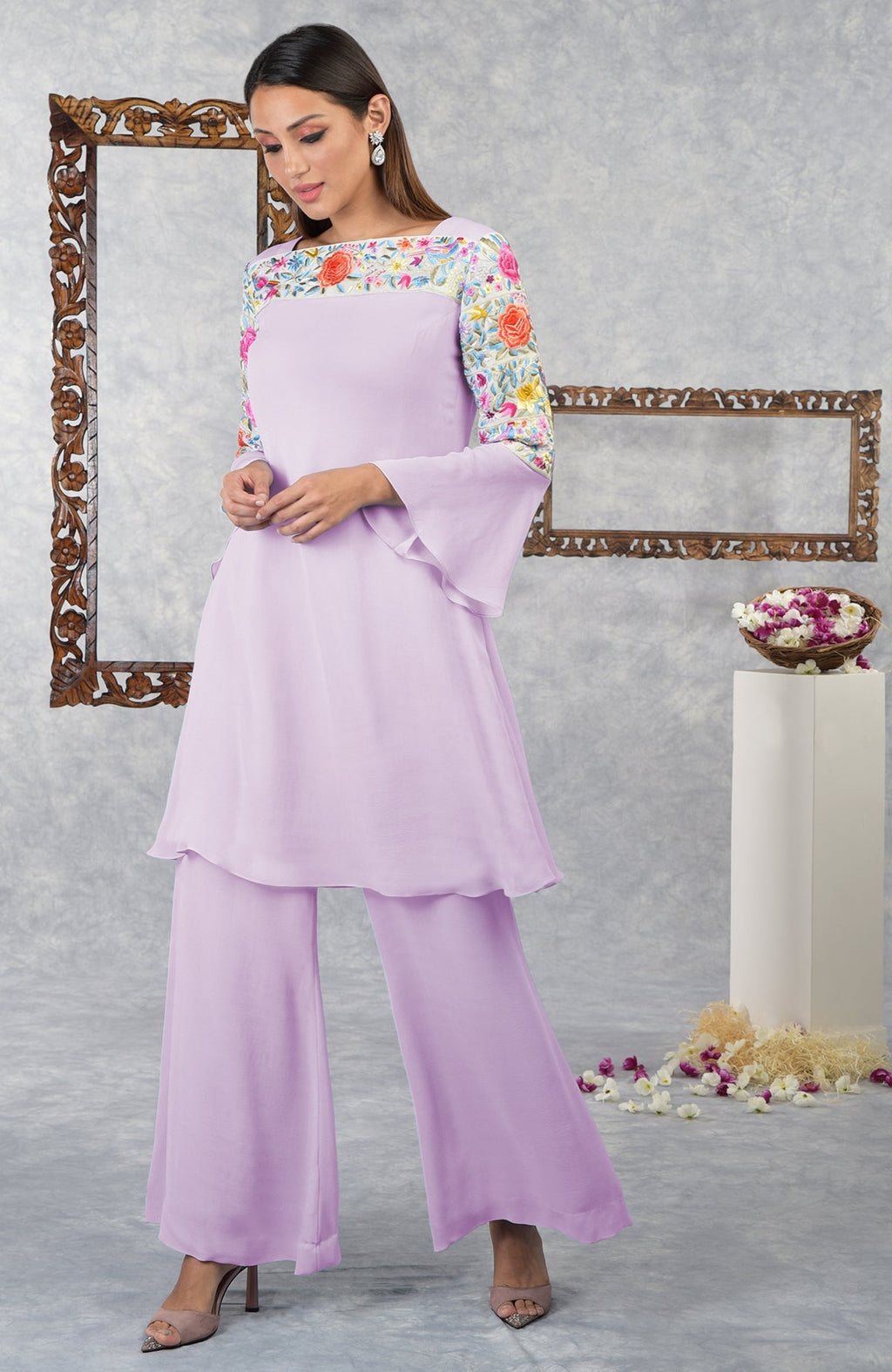 A woman models a lilac kurta set with Parsi Gara floral embroidery.