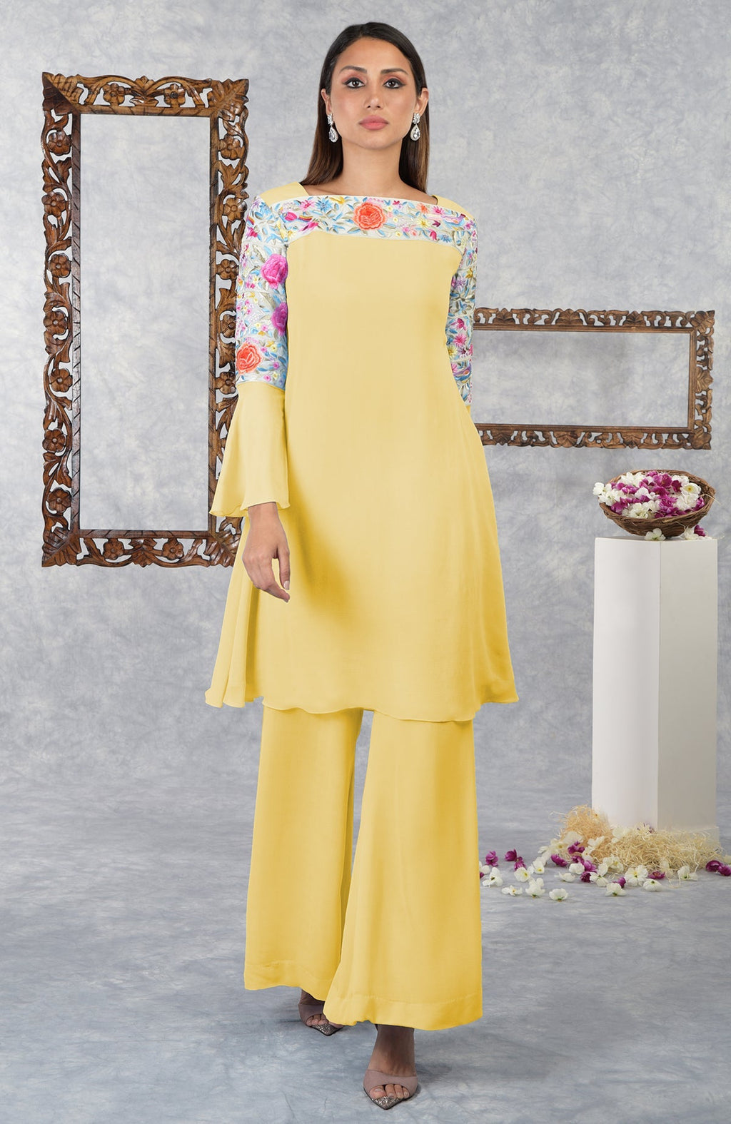 A woman models a yellow Parsi Gara embroidered kurta set with floral details.