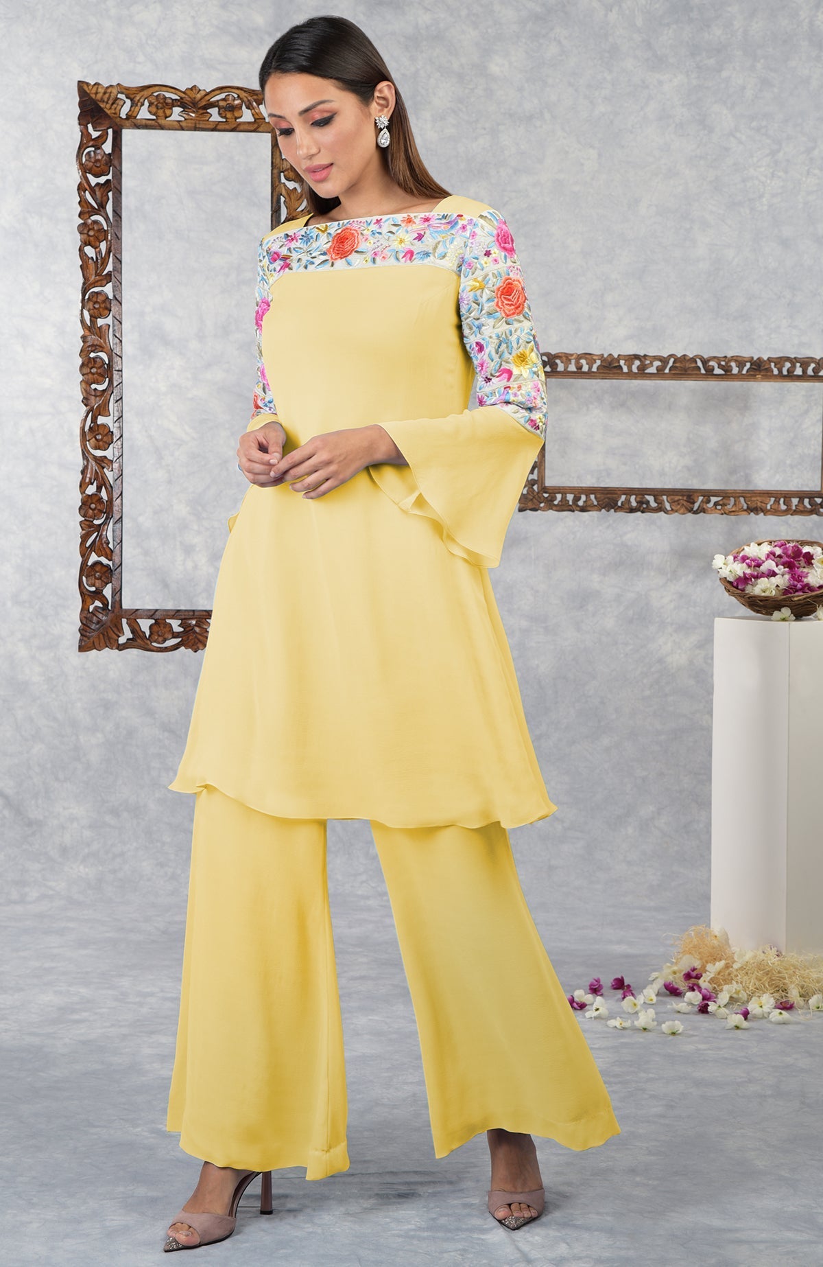 A woman models a yellow Parsi Gara embroidered kurta set with bell sleeves.
