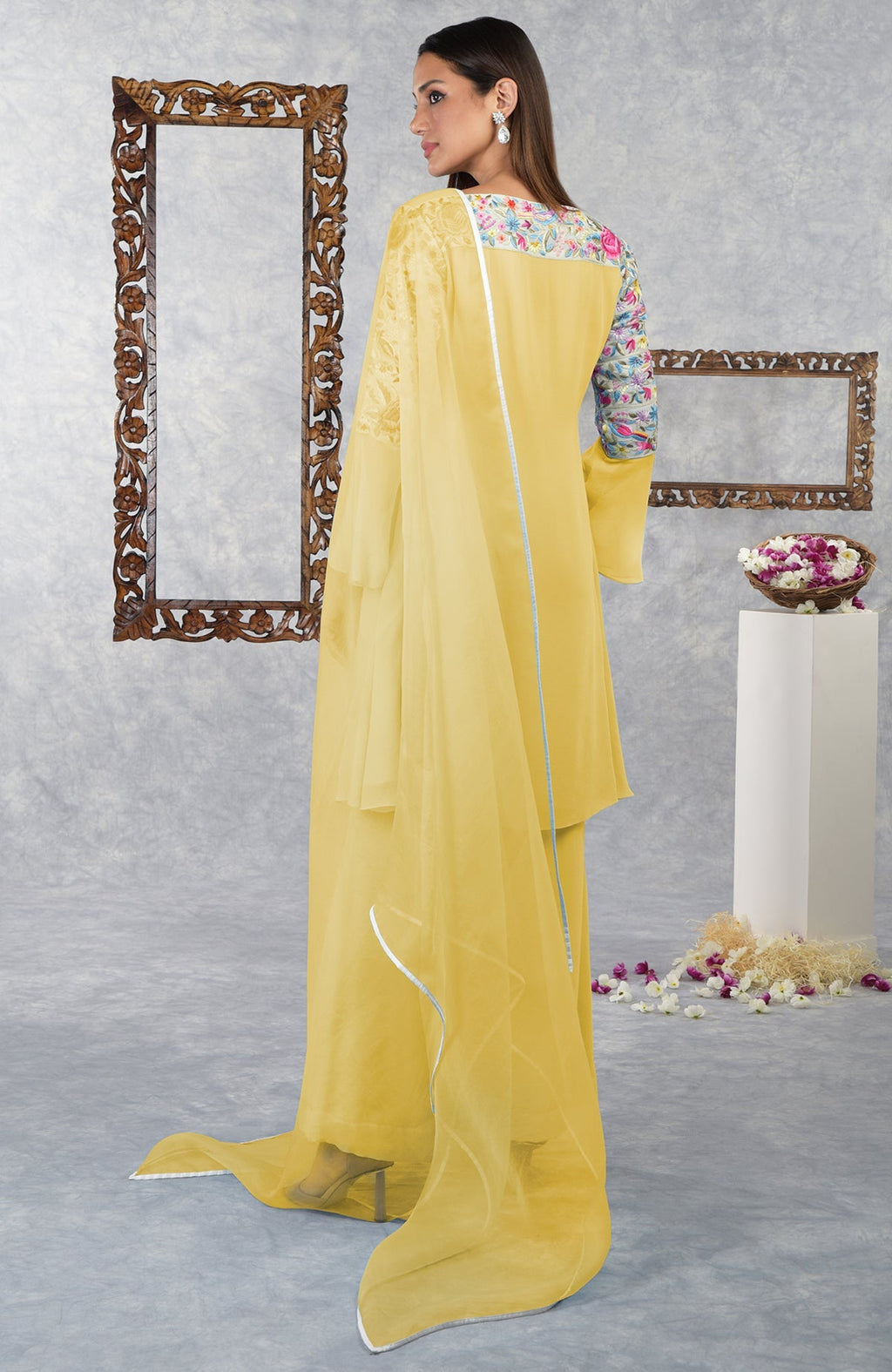 A woman models a yellow Parsi Gara embroidered kurta set with a floral neckline.