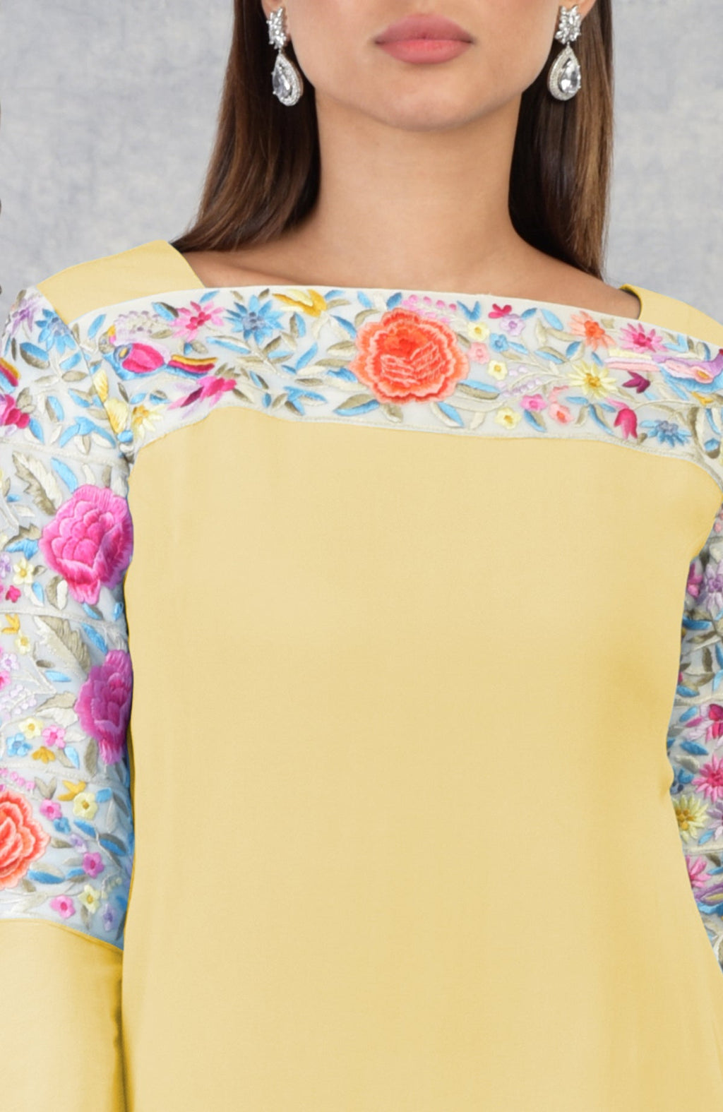 A woman models a yellow Parsi Gara embroidered kurta with a square neckline.