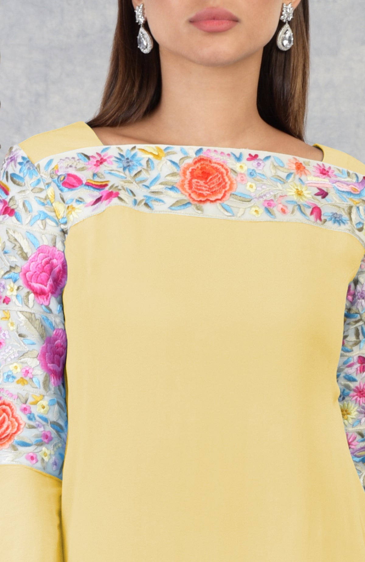 A woman models a yellow Parsi Gara embroidered kurta with a square neckline.