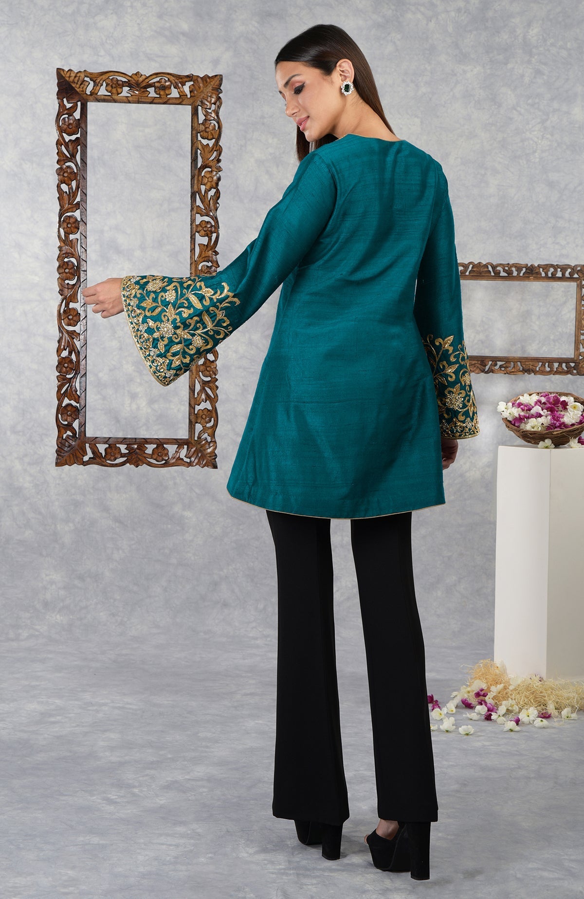 Deep teal raw silk jacket with gold embroidery on sleeves, paired with black pants.