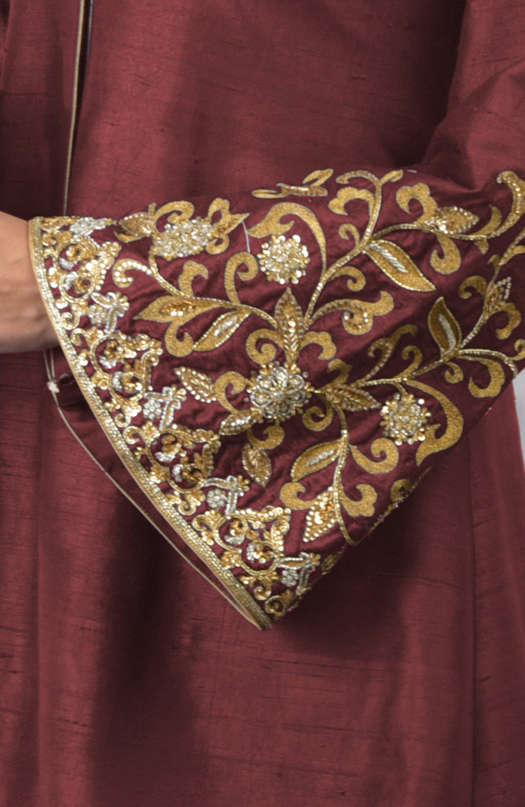 Close-up of a pomegranate-mulled grape raw silk jacket with embroidered sleeve.