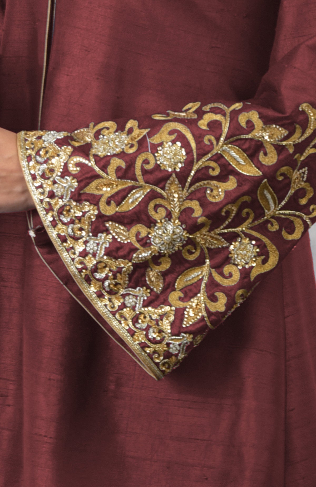 Close-up of a pomegranate-mulled grape raw silk jacket with embroidered sleeve.