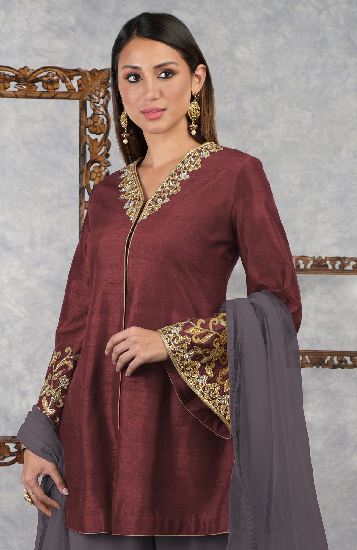 A woman models a pomegranate-mulled grape raw silk jacket set with a dupatta.
