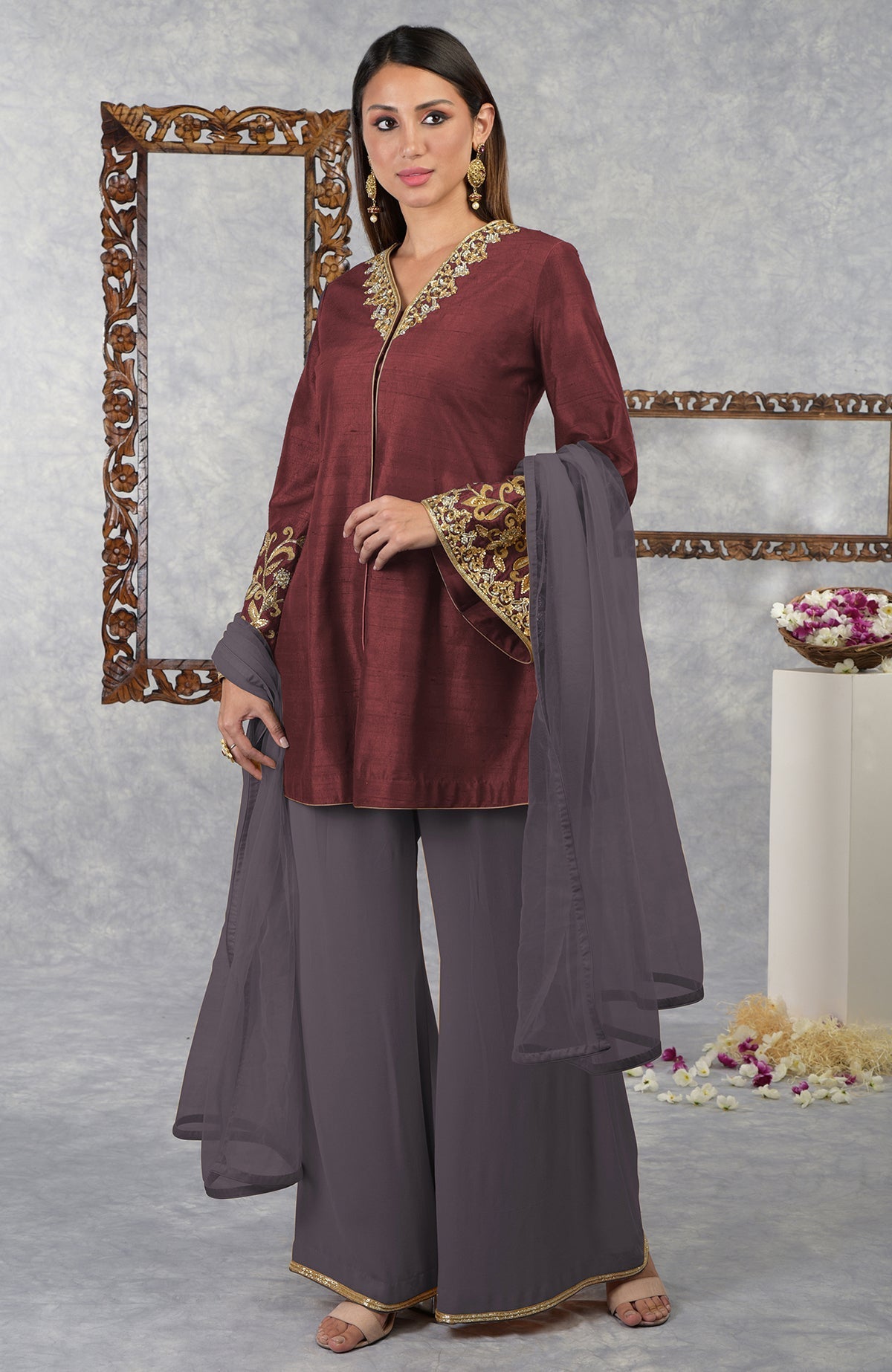 A woman models a pomegranate-mulled grape raw silk jacket set with a dupatta.