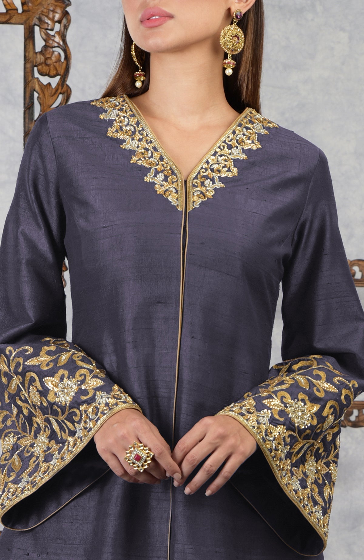 A woman models a smoky violet raw silk hand-embroidered jacket with gold accents.