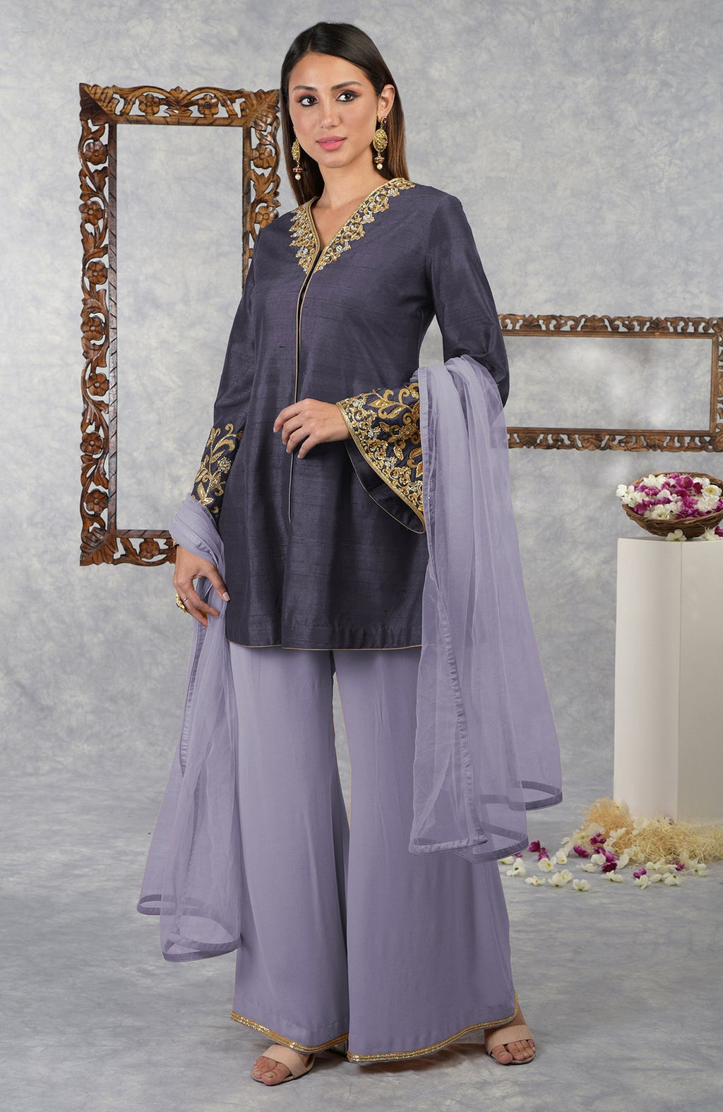 A woman models a smoky violet raw silk jacket set with pastel lilac palazzo and dupatta.