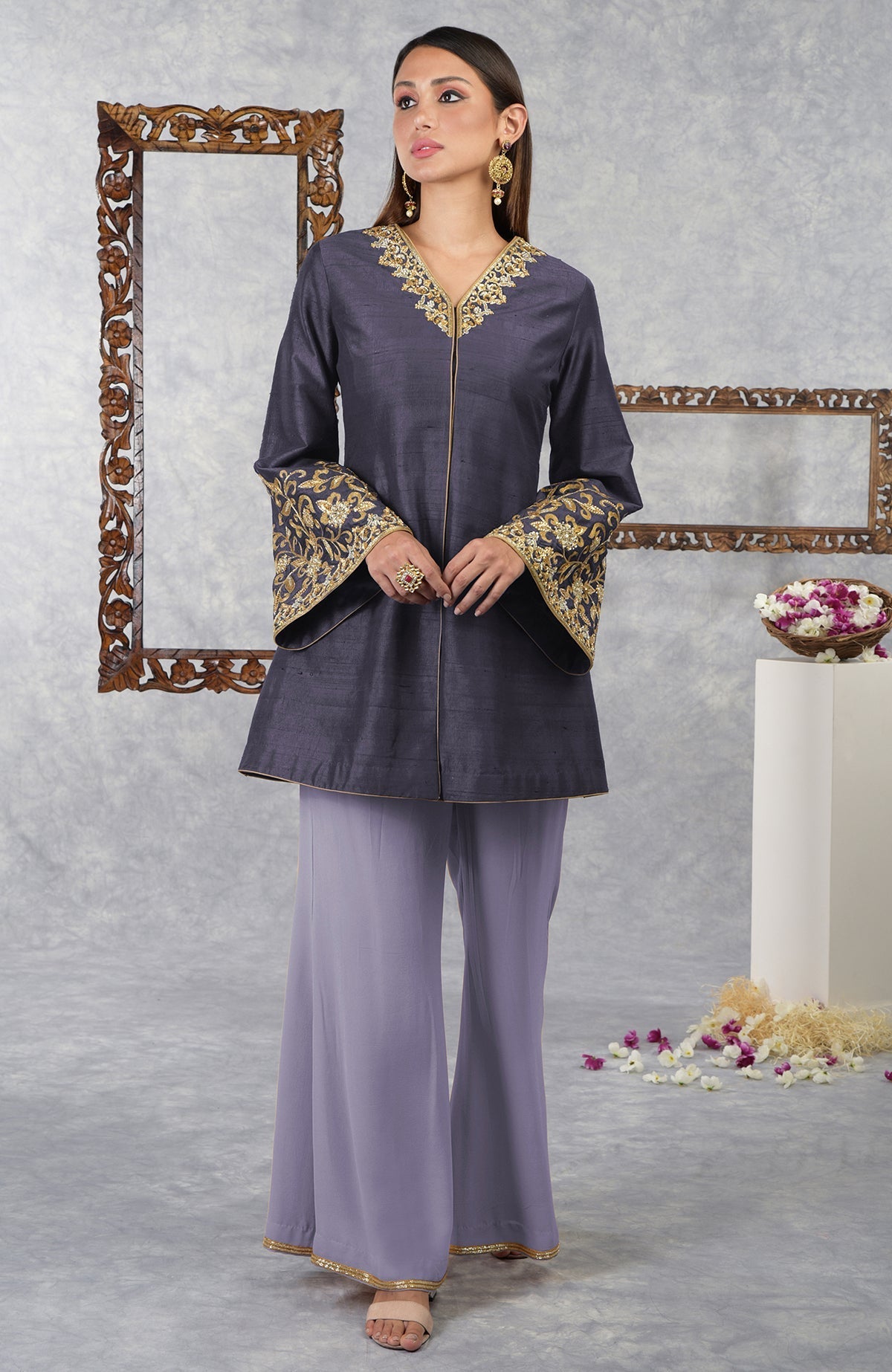 A woman models a smoky violet raw silk hand-embroidered jacket set with pastel lilac pants.