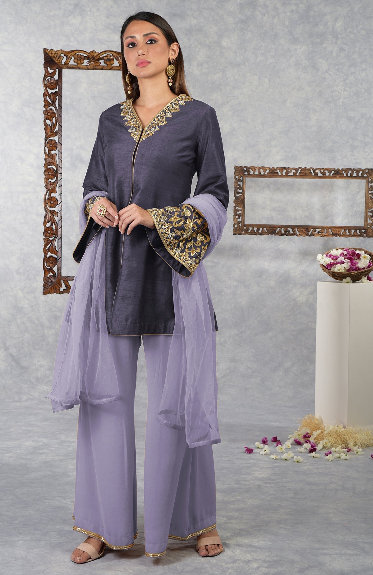 A woman models a smoky violet raw silk hand-embroidered jacket set with a pastel lilac dupatta.