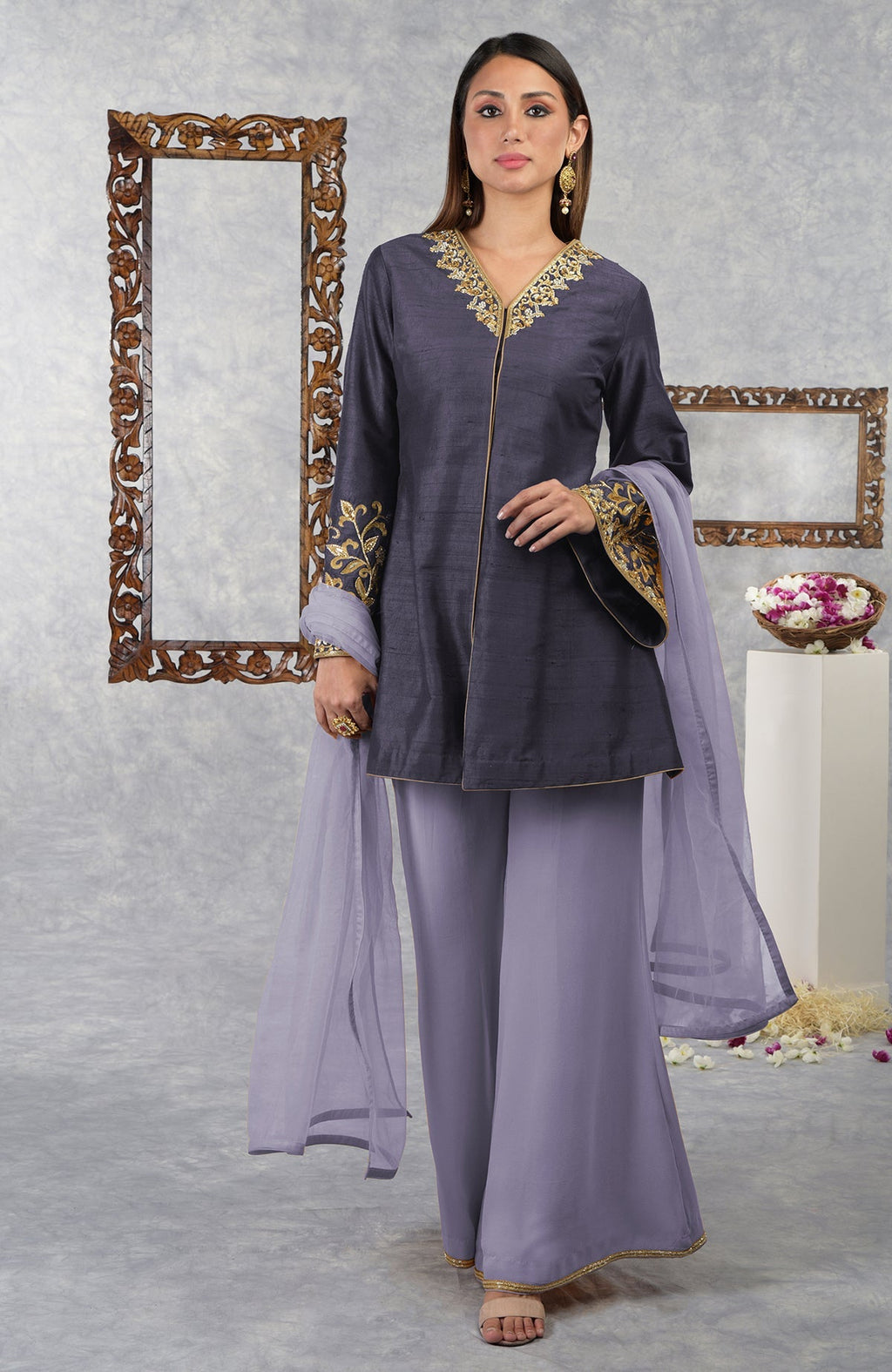A woman models a smoky violet raw silk jacket set with pastel lilac palazzo and dupatta.