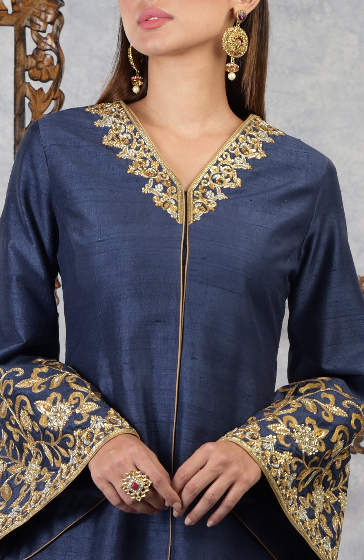 A woman models a navy blue raw silk jacket with gold embroidery.