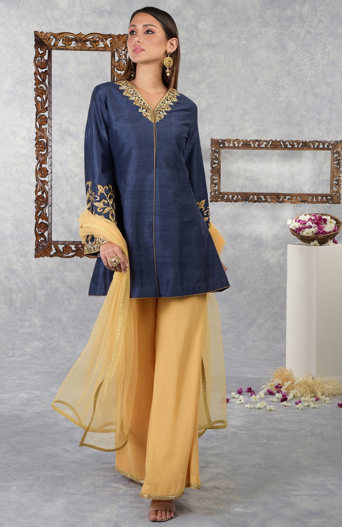 A woman models a navy blue raw silk jacket set with honey yellow palazzo pants and dupatta.