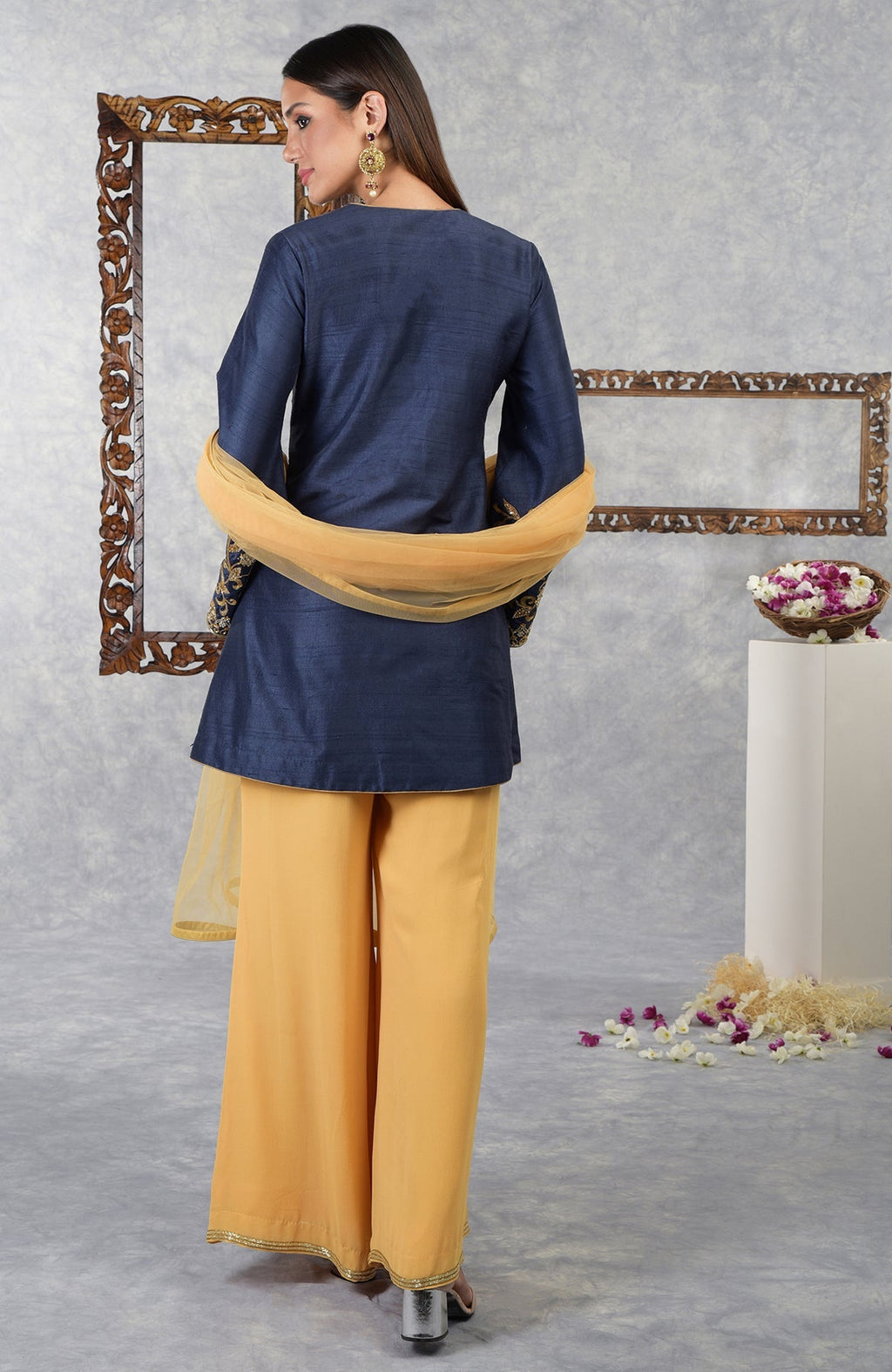 Woman in a navy blue jacket, honey yellow palazzo pants, and a matching dupatta.