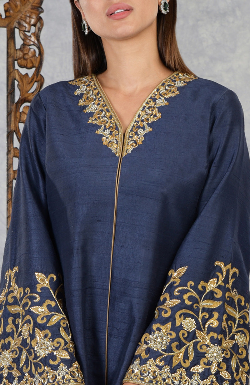 A woman models a navy blue raw silk jacket with gold embroidery on the neckline and sleeves.